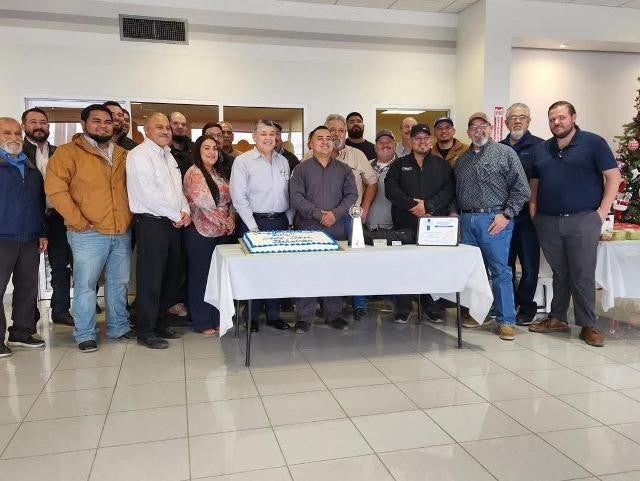 Team celebrates technician award with cake and group photo