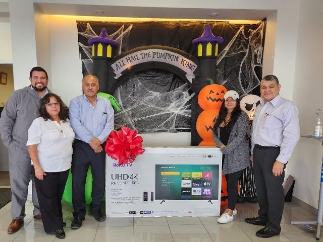 Group posing with TV gift box in Halloween-themed setting