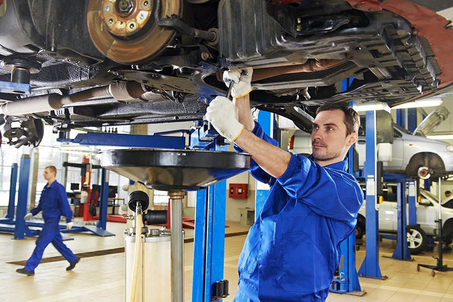 Technician working underneath a lifted car at a service center